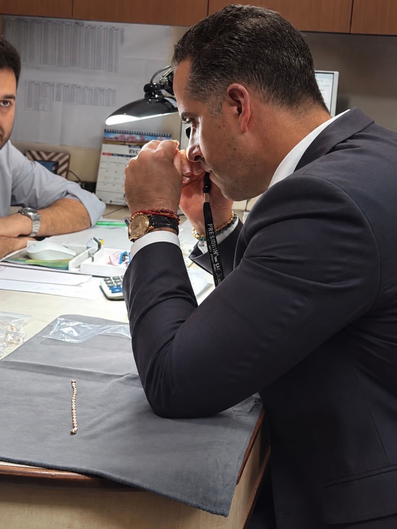 Hombre con traje examinando minuciosamente una joya con una lupa de aumento profesional.